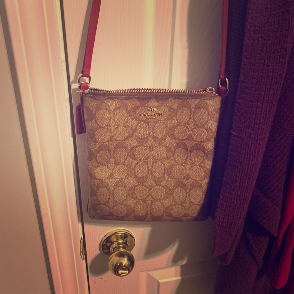 This is a coach signature bag with a red strap